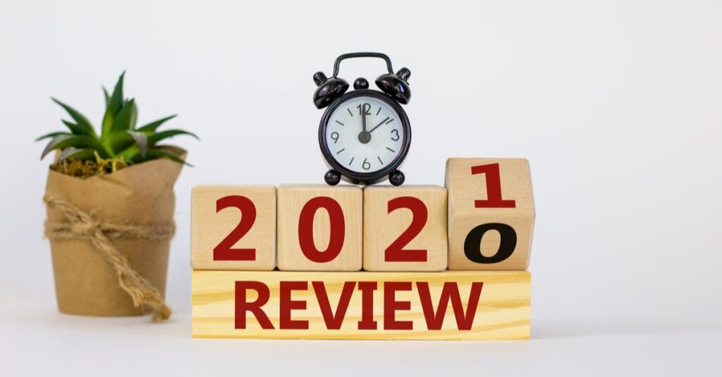 Analog clock with wooden blocks showing '2021' and '2020' with 'REVIEW' text.