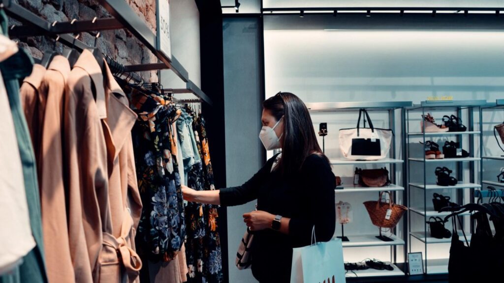 Woman shopping for clothes while wearing a face mask in a boutique.