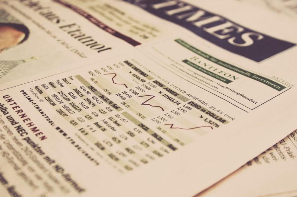 Close-up of a newspaper financial section with stock market data and graphs.