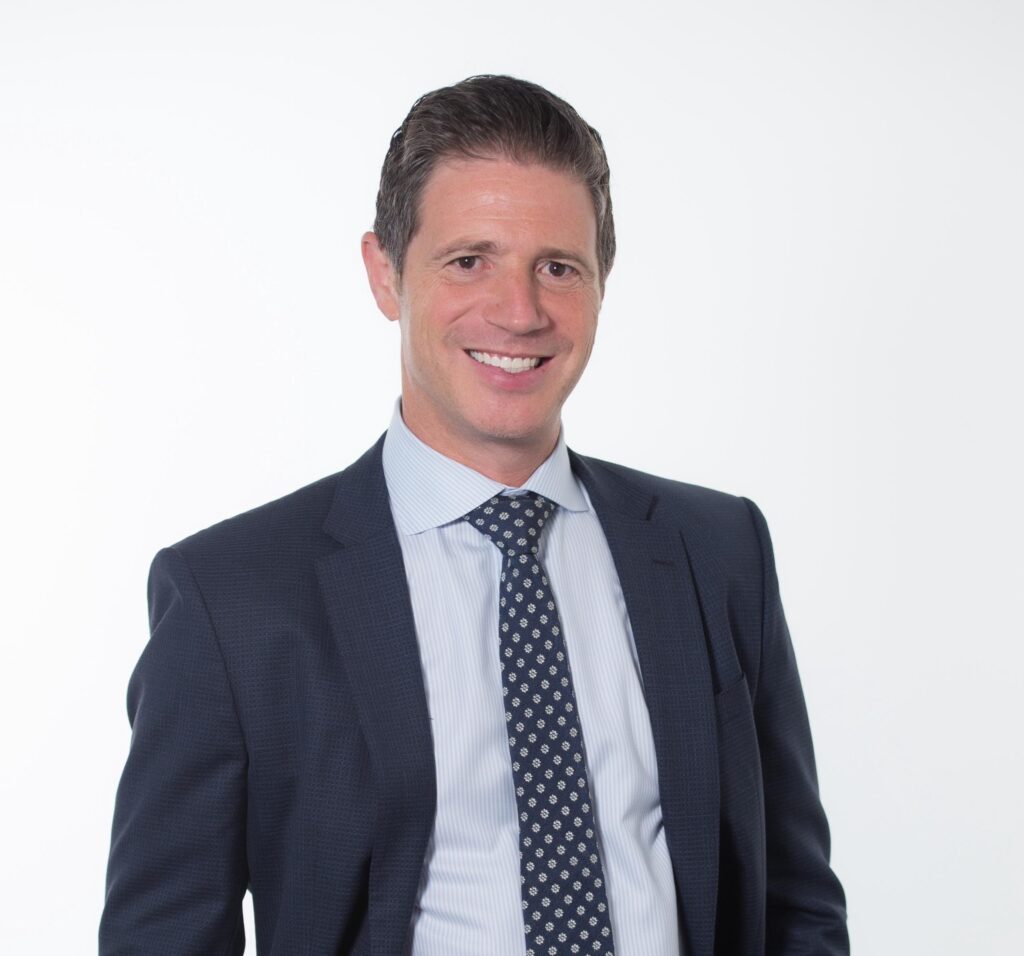 Confident businessman in a dark suit and patterned tie.