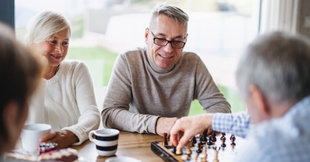 Smiling seniors playing chess at table